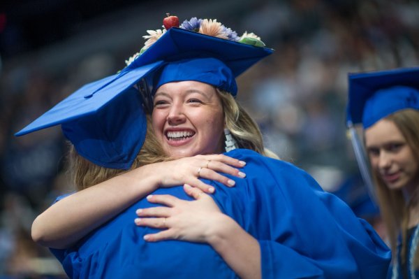  Two college graduates hug and smile