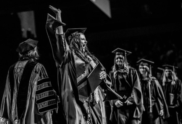  A college graduate pumps a fist in the air after receiving their diploma. 