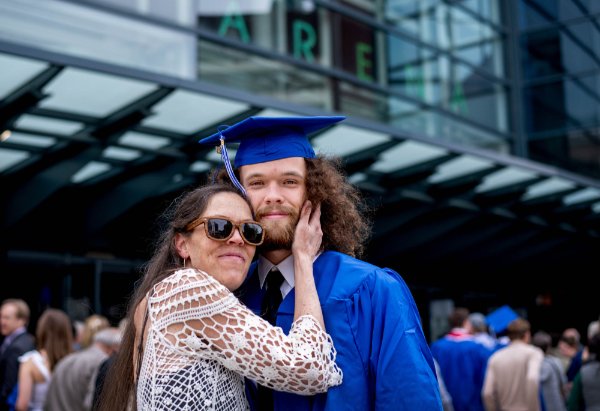 A mother and son pose for a photo before graduation.