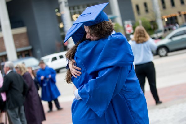 Two graduates hug outside the Van Andel Arena.
