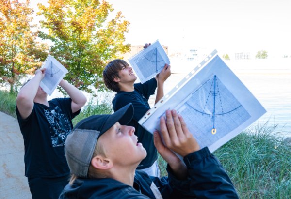 Crossroads Charter Academy students from Big Rapids Aiden Smith, top, A.J. Bacon, front, and Justin Croff Jr. use clinometer sheets to measure the height of a tree while taking part in an educational visit to the Annis Water Resources Institute.