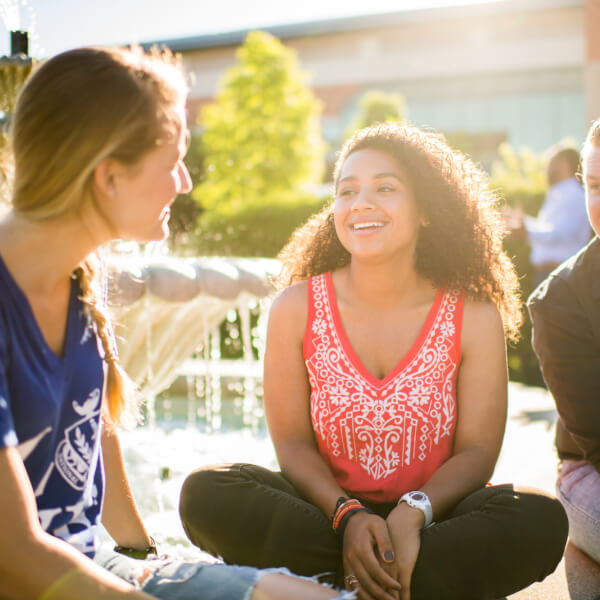 A photo of students talking by a fountain on campus. 