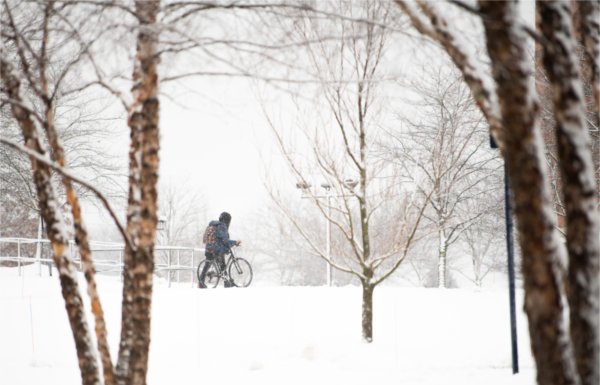  A college student pushes their bike through a snowy campus. 