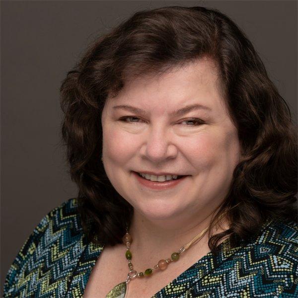 A GVSU professor smiles while posing for a photo.