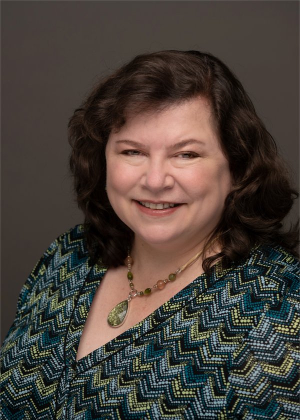A GVSU professor smiles while posing for a photo.