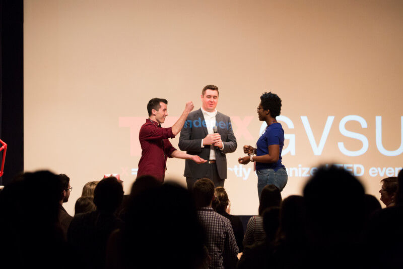 three people on stage during presentation