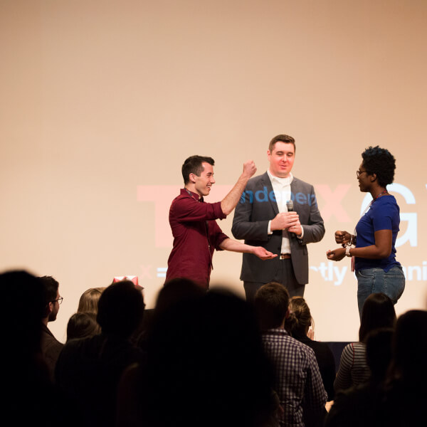 three people on stage during presentation