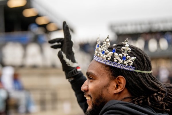  Close up of a person smiling while wearing a silver and blue jeweled crown.