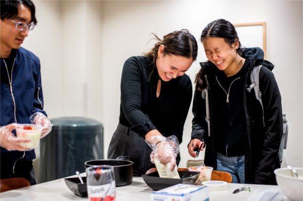  Two people laugh together as they prepare food at a table.