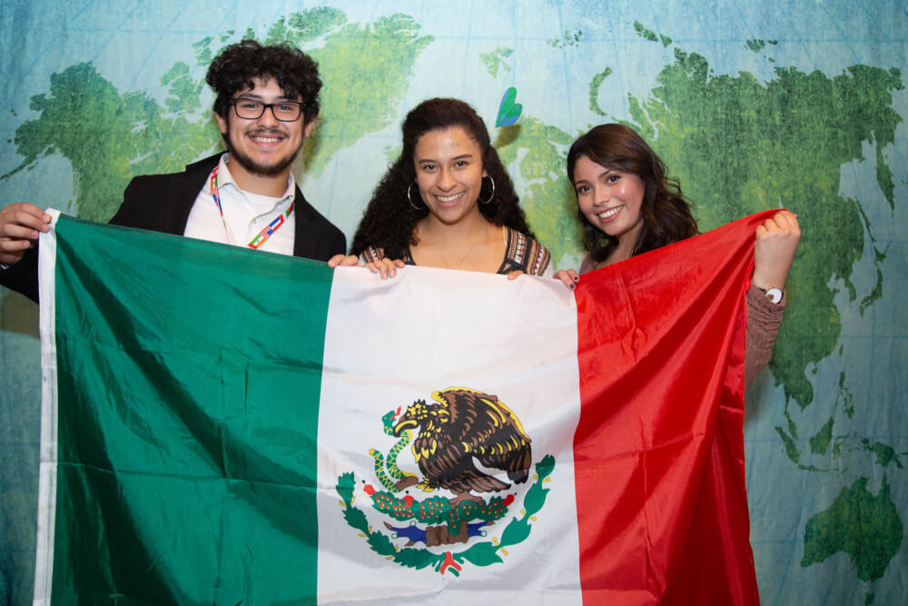 three people holding a flag from Mexico