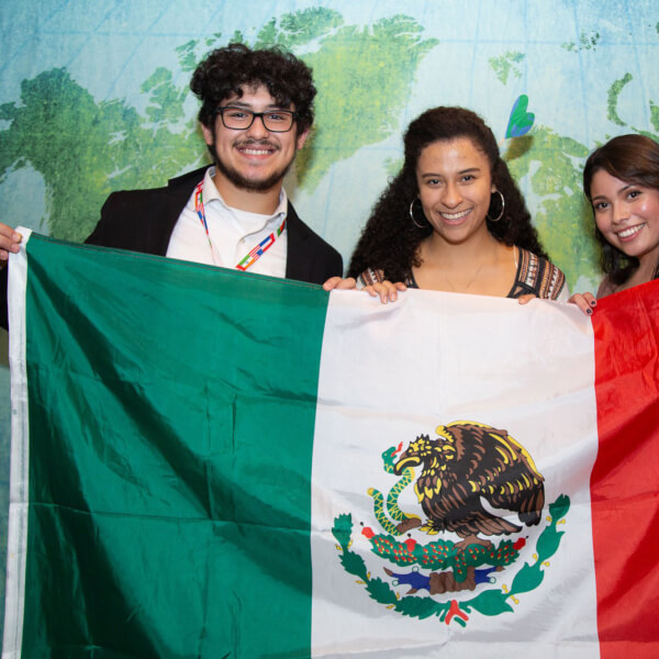 three people holding a flag from Mexico
