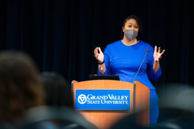 Littisha Bates speaks from behind a podium, gestering with her hands