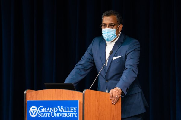 Bobby Springer stands behind a podium, he is wearing a mask