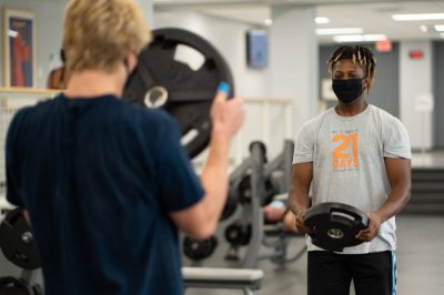 Two men wearing face coverings lift weights and work out at Grand Valley's recreation center on Monday, Sept. 14.