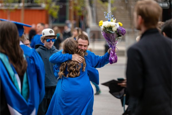 A soon-to-be graduate shares a hug with a family member before the Commencement ceremony to begin at Van Andel Arena May 2.
