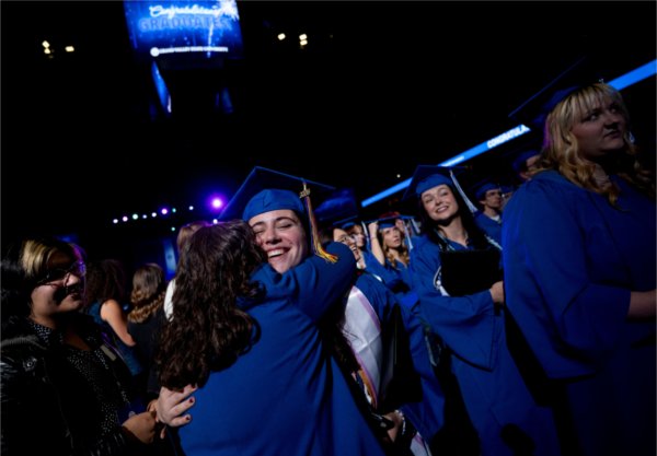 Annah Stang hugs Katie Perschbacher from the Dean of Students office, left, after Stang earned a degree in marketing during Saturday afternoon&#8217;s Commencement. 