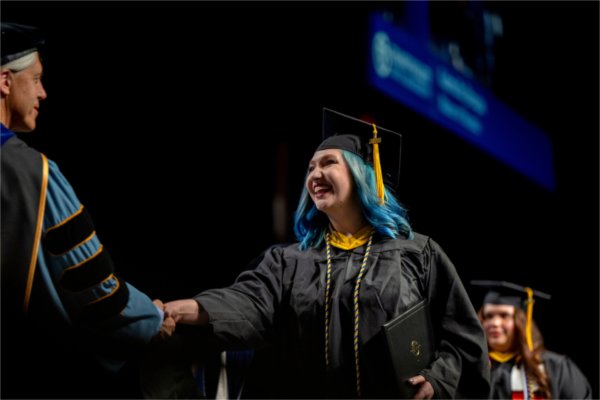 A graduate receives their diploma during the Commencement ceremony at Van Andel Arena on May 2.