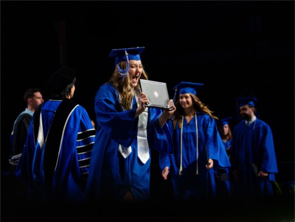 Avery Howe, who graduated with a bachelor of science in allied health sciences, excitedly holds up her diploma while walking across the stage during Commencement at Van Andel Arena May 2. 