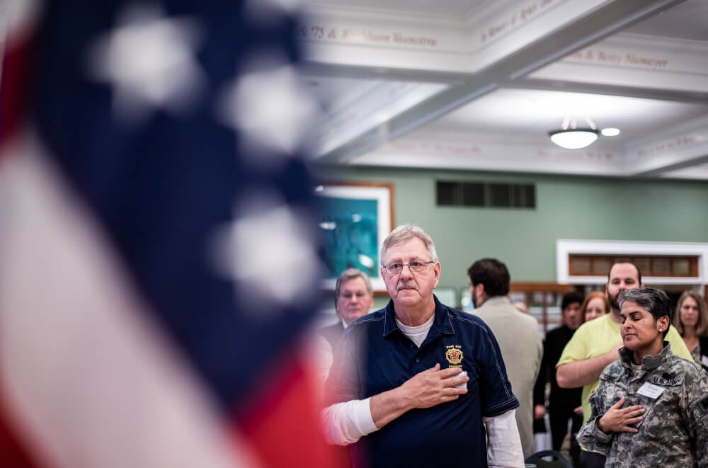 Photo of a veteran facing the American Flag during the singing of the National Anthem.