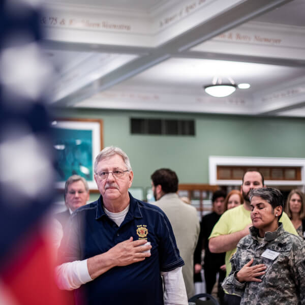 Photo of a veteran facing the American Flag during the singing of the National Anthem.