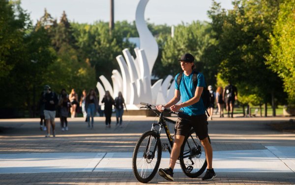 Student walking his bike on campus.