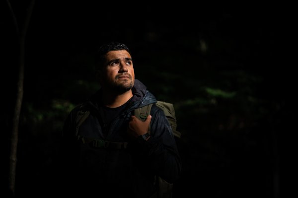 A portrait of a student veteran in the woods with light hitting their face. 