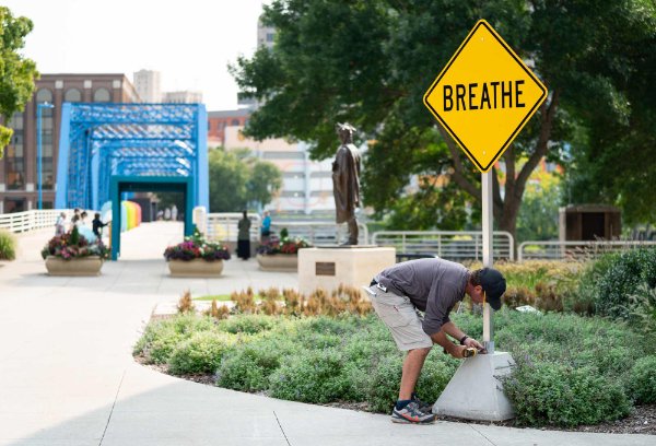 A person installs a sign that reads "BREATHE." 
