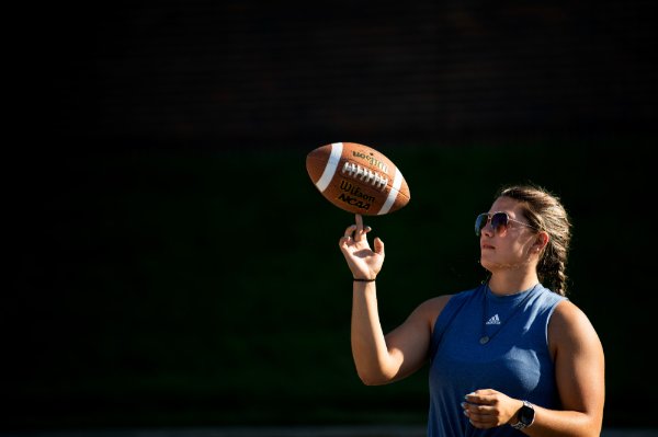 A college student twirls a football on their finger. 
