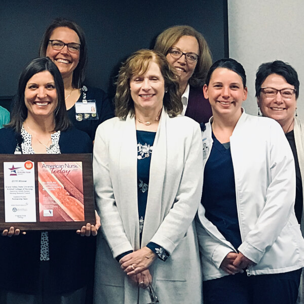 group of women in two rows, one holding plague
