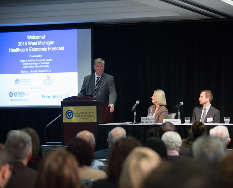 one person at podium, two people at table