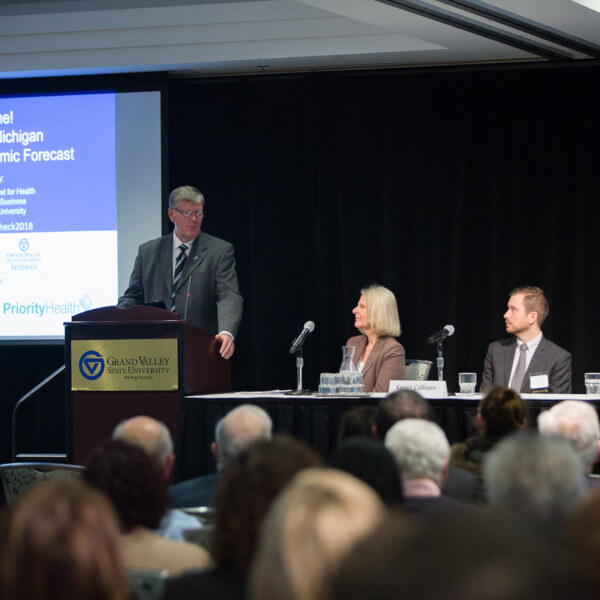 one person at podium, two people at table
