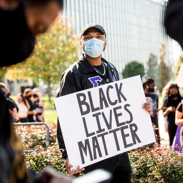 A man in a crowd holds a "Black lives matter" sign