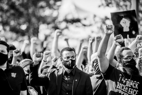 A black and white photo of a group of people with their fists raised at the GVSU solidarity march on the Allendale Campus on Friday, October 9.