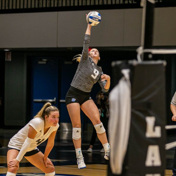 Volleyball player serves the ball during a game.