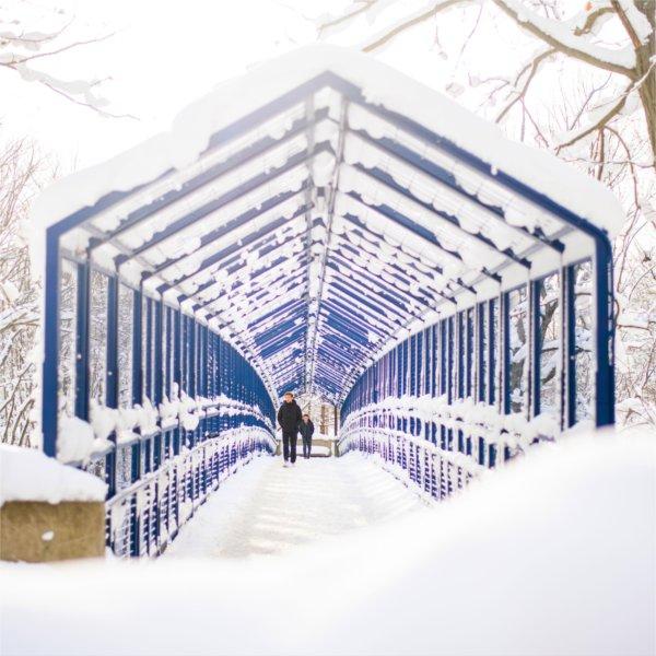 Students walk over the blue Little Mac Bridge surrounded by the results of a recent snowfall.