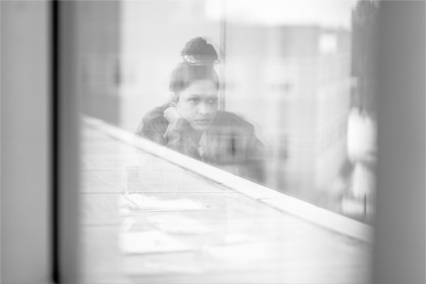  A person studies in a library as seen through blurry glass. 
