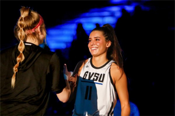  A college female basketball player smiles and does a special handshake before the start of a game. 