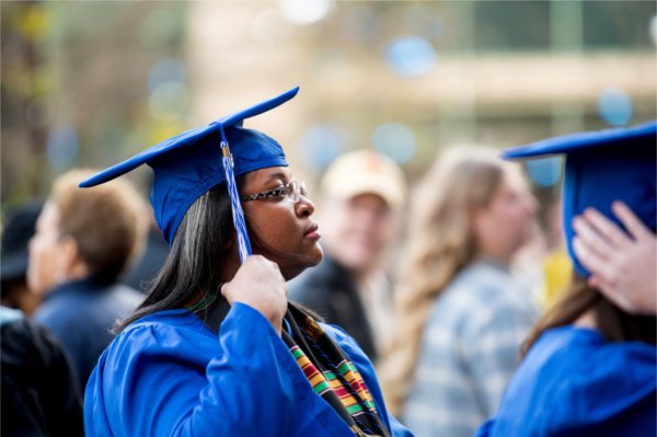 A person touches the tassel hanging from her graduation cap. 