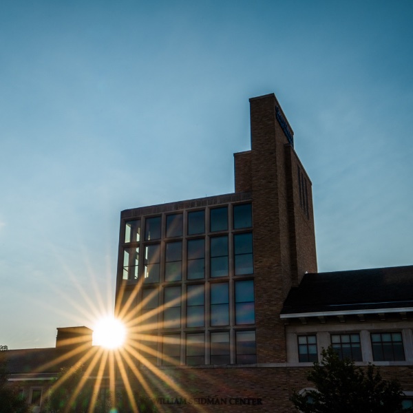 The sun shines through the Seidman College of Business building.
