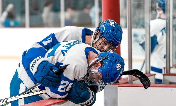 A hockey player in blue consoles his teammate after losing the game. 