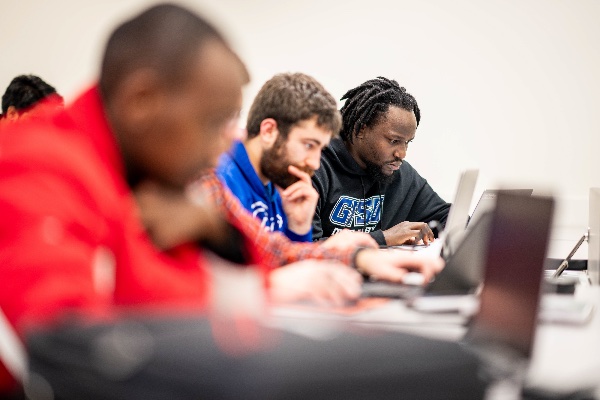 A row of college students work intently on their computers. 