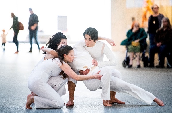 College dancers perform a modern dance routine wearing all white. 