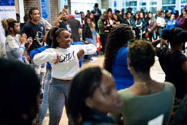A college student dances in a large group during a black student organization showcase.  