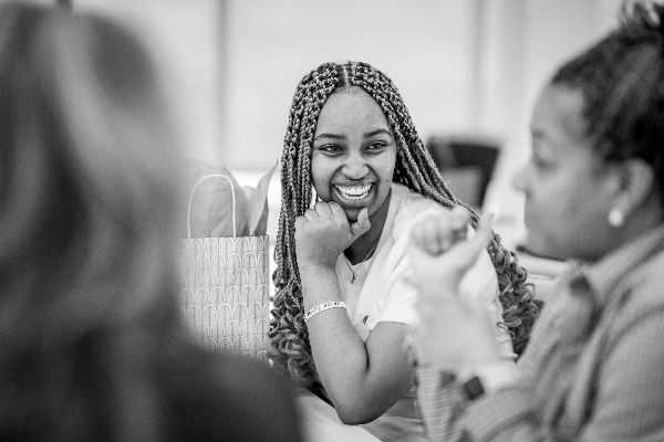 A person sits at a table smiling with others.