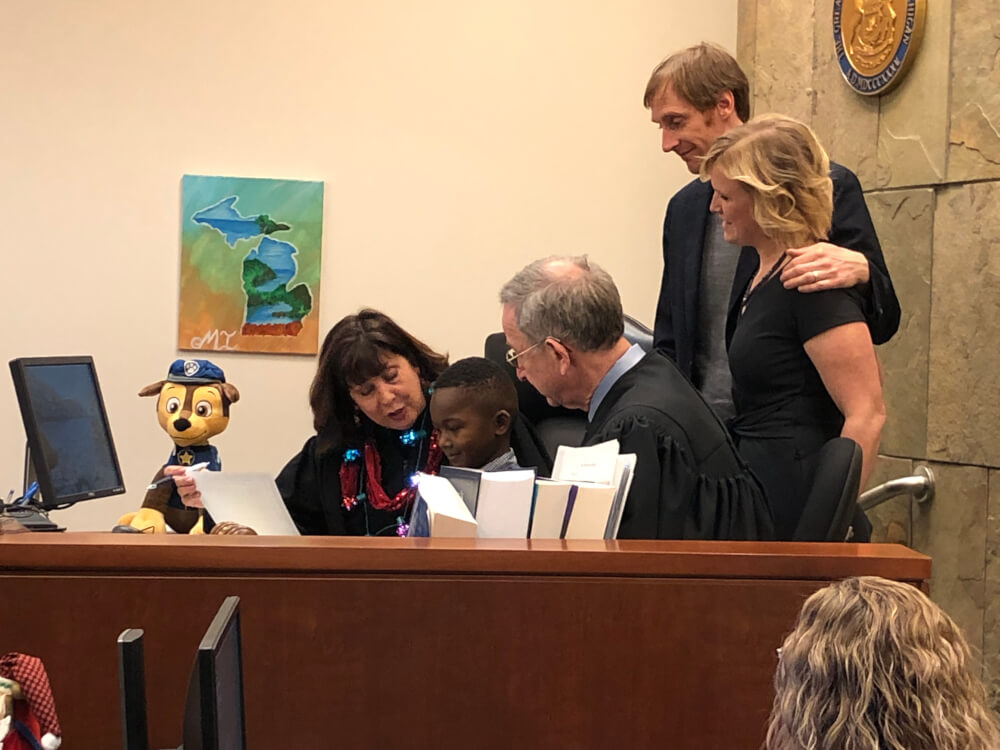 Kent County 17th Circuit Court Judge Patricia Gardner makes the adoption of Michael official as Michigan Supreme Court Justice Stephen J. Markman and parents David Eaton and Andrea Melvin observe.