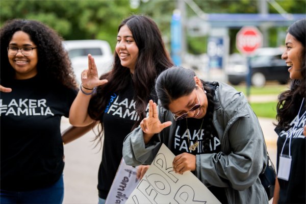 A group of students with Laker Familia, from left, Arianna Westbrooks, Luz Martinez, Lesley Mendez-Velasquez and Lucero Orduna-Rivera laugh together as they welcome students with posters and Anchor Up hand signs during the first day of Valley Campus move-in.  
