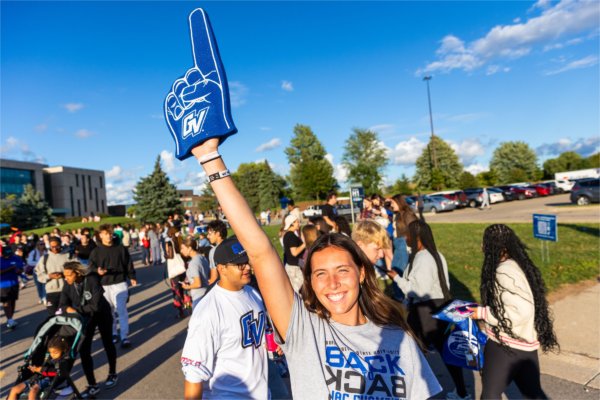  A smiling person holds up her arm, wearing a &#8216;GV&#8217; branded foam finger on her hand.