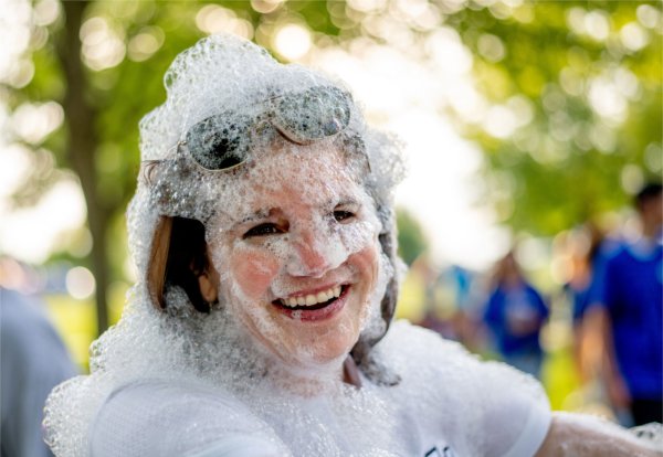  A person covered in foam bubbles smiles at the camera.