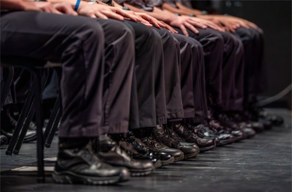 A row of seated people wearing black pants and shoes.