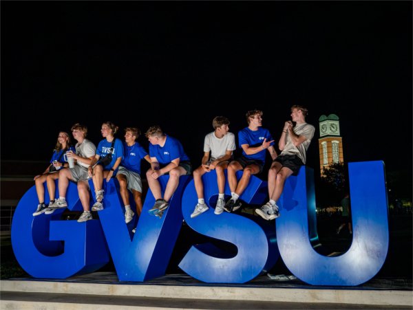 Students sit on top of the GVSU Laker Letters at night.